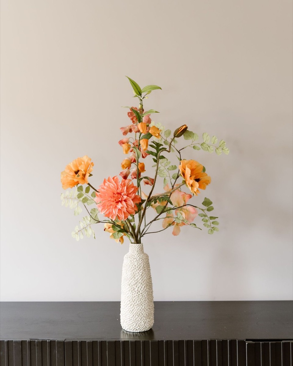 Zijden boeket in oranje en perzik in een witte vaas