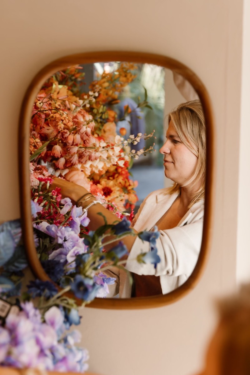 Sarah weerspiegeld in een spiegel tussen de bloemen